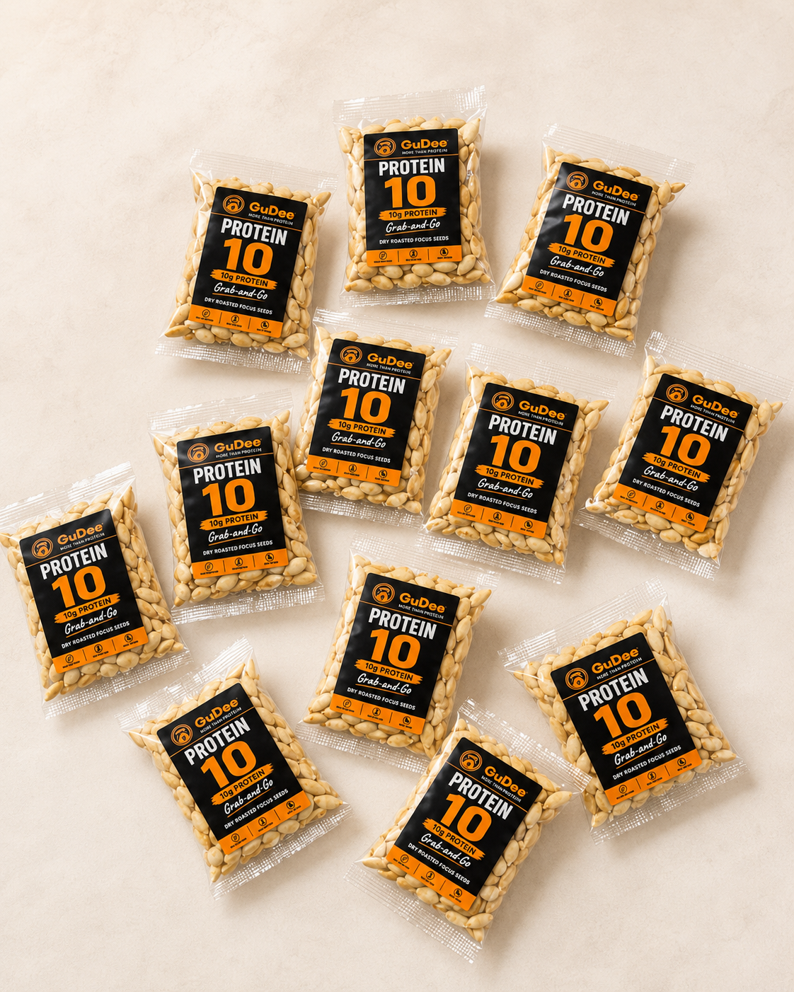 Nine clear packs of GuDee Protein 10, grab-and-go protein packs arranged on a light beige textured surface. Each pack contains 10g protein of dry-roasted Egusi seeds.