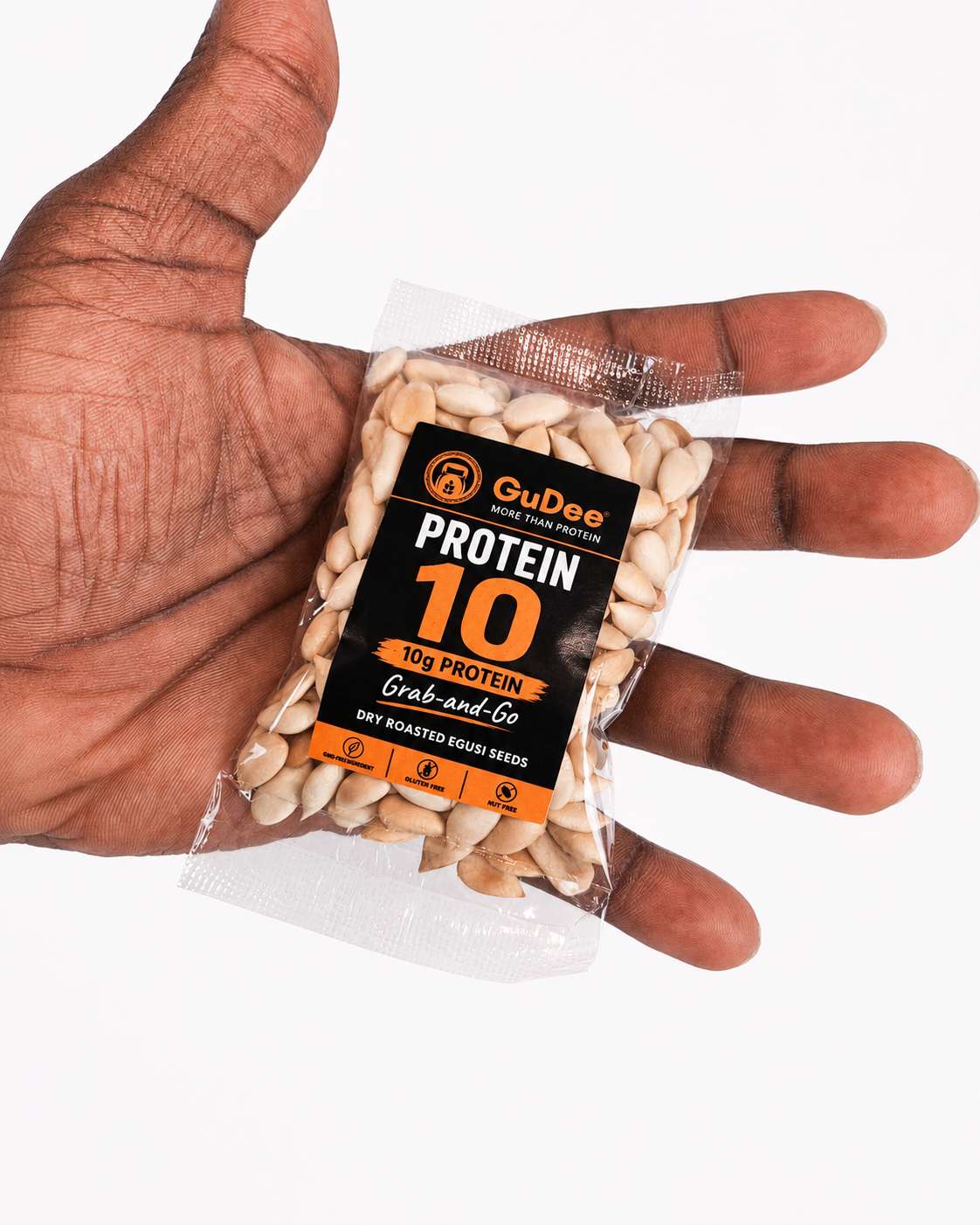 A hand holding a pack of GuDee Protein 10 Grab-and-Go dry-roasted Egusi seeds against a plain white background.